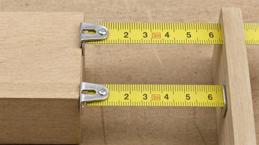Two tape measure hooks shown pulled over an edge and pushed against a surface, revealing their different sliding positions.